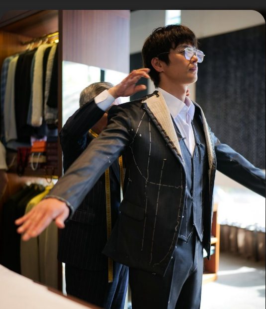 Master tailor styling a client with a bespoke tie